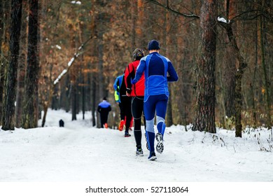 Group Of Runners Athletes Run In Snow Forest During Winter Marathon