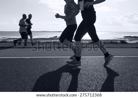Group of runners compete in the race on coastal road