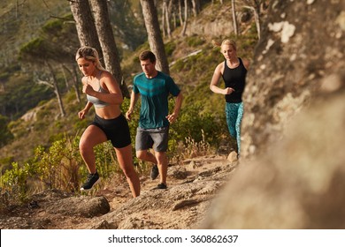 Group of runners running on rocks up a hill. Young people running cross country. - Shutterstock ID 360862637