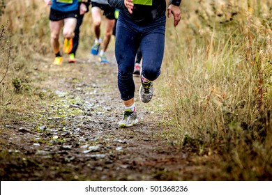 Group Runners Running Uphill In Autumn Trail Of Mud And Stones