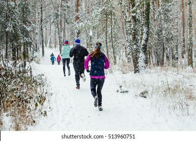 Group Of Runners Running In Winter Forest Marathon In Falling Snow