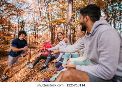 Group Of Runners Sitting And Chatting After Running. Forest In Autumn Exterior. Teamwork And Healthy Lifestyle Concept.