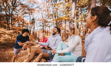 Group Of Runners Sitting And Chatting After Running. Forest In Autumn Exterior. Teamwork And Healthy Lifestyle Concept.