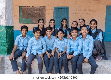 Group of rural indian school students sitting together in blue school uniform looking at camera - Powered by Shutterstock