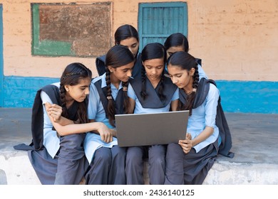 Group of rural school girls in uniform sitting in school corridor working on laptop - concept of digital education - Powered by Shutterstock