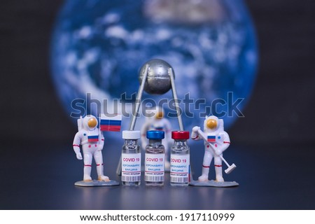 Group of russian vaccines named after a well-known russian satellite against Covid 19 virus with a group of small astronauts. Out of focus. Tag text reads, corona virus injection only.