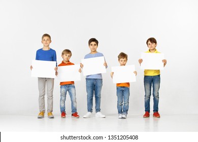 Group Of Sad Children With A White Empty Banners Isolated In Studio Background. Education And Advertising Concept. Protest And Childrens Rights Concepts.