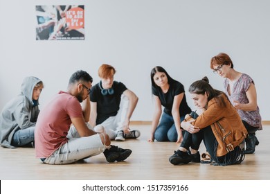 Group Of Sad Teenagers Sitting In A Circle During Therapy