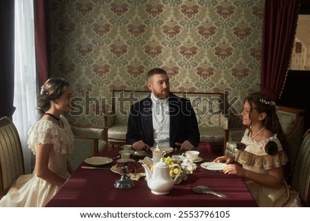 Group scene at dining table featuring three elegantly dressed figures conversing in classical interior