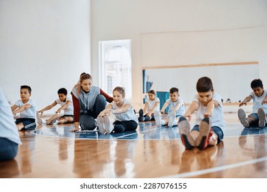 Group of school children doing stretching exercise with help of sports teacher during PE class. - Powered by Shutterstock