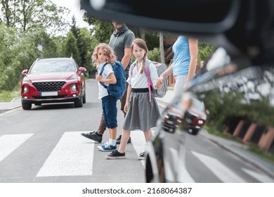 Group of school children goes through the pedestrian crossing in the street, right in front of the car - Shutterstock ID 2168064387