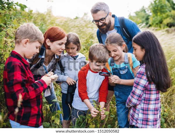 Group of school children with teacher on field\
trip in nature, learning\
science.