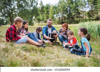 Group of school children with teacher and windmill model on field trip in nature.
