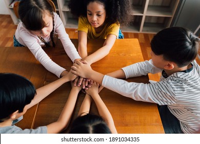 Group of school friends with hands stacked one on top of another, friendship, support, togetherness. Multiethnic school children with hands touching on top of each other - Powered by Shutterstock