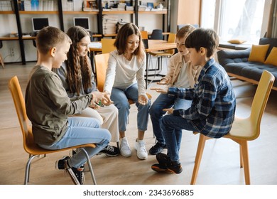 Group of school kids playing rock-paper-scissors game while sitting in circle in library - Powered by Shutterstock