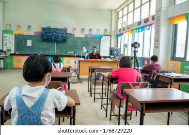 Gruppe von Schulkindern mit Lehrer, die in der Grundschule im Klassenzimmer sitzen.