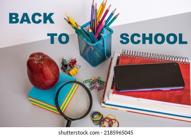 Group of school supplies and books over a gray background, red apple and mobile phone,  back to school concept - Powered by Shutterstock