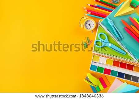 Group of school supplies on orange background. Top view. Copy space.