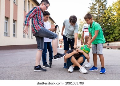 Group Of Schoolboys Bullying A Sad And Upset Looking Boy.