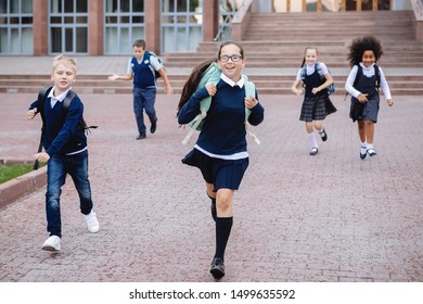 Group Of Schoolchildren In Uniform Are Running Down The Stairs Out Of School.