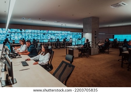 Group of Security data center operators working in a CCTV monitoring room looking on multiple monitors Officers Monitoring Multiple Screens for Suspicious Activities Team working on the System Contr