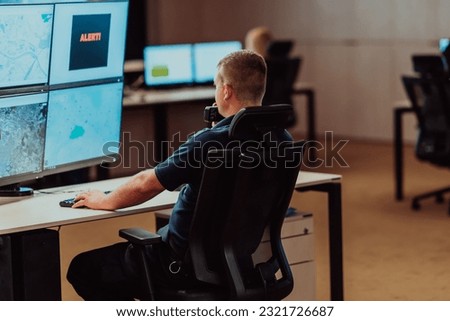 Group of Security data center operators working in a CCTV monitoring room looking on multiple monitors.Officers Monitoring Multiple Screens for Suspicious Activities