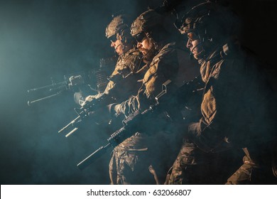 Group of security forces in Combat Uniforms with rifles, lined in the face of danger. Facing enemy, they stand boldly and ready to protect the nation. Studio contour silhouette shot, backlight