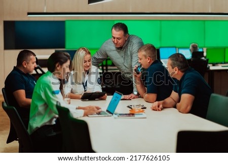 Group of security guards sitting and having briefing In the system control room They're working in security data center surrounded by multiple Screens