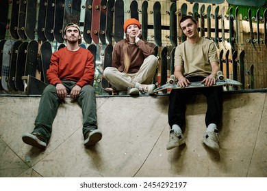 Group of self-confident young male and female skateboard riders in streetwear sitting relaxed in skatepark and looking at camera - Powered by Shutterstock