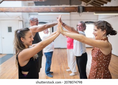 Group of senior Caucasian dancers joining their hands together. Happy retired dance students rising their joined hands up with teacher in studio. Dance, hobby, healthy lifestyle concept - Powered by Shutterstock