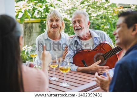 Group of senior enjoy party at home, drinking white wine, sing songs to relax