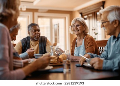 Group of senior friends communicating while eating lunch in nursing home. Focus is on happy woman. - Shutterstock ID 2281239193