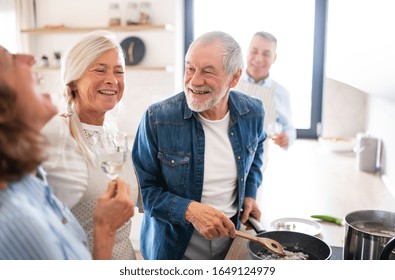 Group Of Senior Friends At Dinner Party At Home, Cooking.