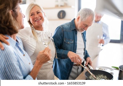 Group Of Senior Friends At Dinner Party At Home, Cooking.