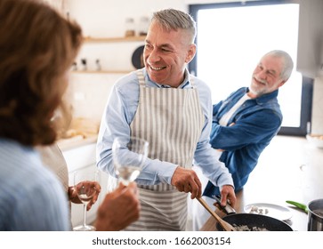 Group Of Senior Friends At Dinner Party At Home, Cooking.