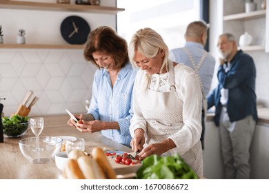 Group Of Senior Friends At Dinner Party At Home, Cooking.