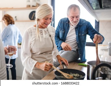 Group Of Senior Friends At Dinner Party At Home, Cooking.