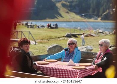 A group of senior friends engages in lively conversation with the waitress, discussing their meal preferences and savoring the delightful camaraderie that accompanies their dining experience - Powered by Shutterstock