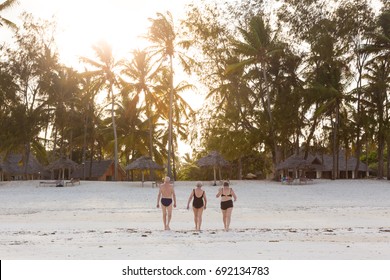 Group Of Senior Friends Enjoying Beautiful Sunset Walk On The Beach. Exsotic Travel Vacation Retirement Lifestyle Concept.