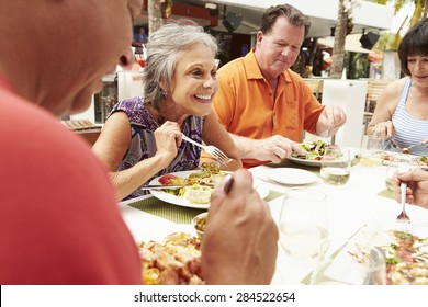 Group Of Senior Friends Enjoying Meal In Outdoor Restaurant