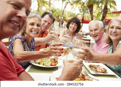 Group Of Senior Friends Enjoying Meal In Outdoor Restaurant