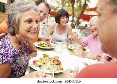 Group Of Senior Friends Enjoying Meal In Outdoor Restaurant