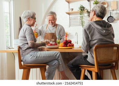 Group Of Senior Friends Having Party Indoors, Cooking And Talking Positive Conversation In Senior Daycare,asian Senior Male Standing In Kitchen And Relaxing At Home While Eating A Healthy Food Recipe