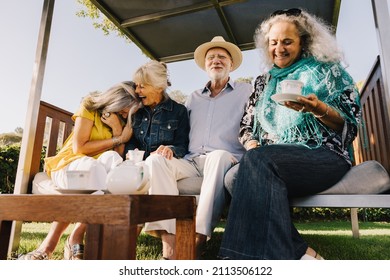 Group Of Senior Friends Laughing Happily While Having Tea Together. Cheerful Elderly Friends Enjoying Their Summer Vacation At A Spa Resort. Senior Citizens Having Fun Together After Retirement.