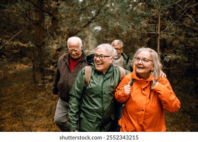 Group of senior friends laughing together on forest hike in raincoats - Powered by Shutterstock