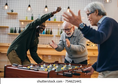 Group Of Senior Friends Playing Foosball At Bar