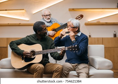 Group Of Senior Friends Playing Music Together With Guitars And Harmonica