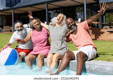 Group of senior friends sitting by pool, laughing and enjoying drinks together. poolside, leisure, fun, seniors, summer, gathering, unaltered - Powered by Shutterstock