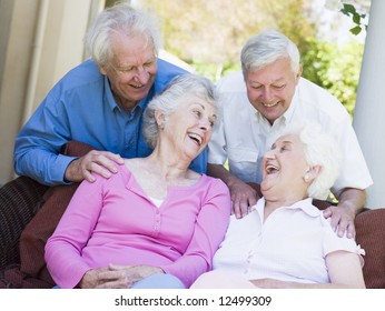 Group Of Senior Friends Sitting On Garden Seat Laughing