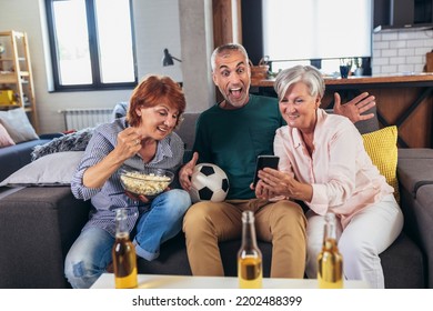 Group Of Senior Friends Support Favorite Sports Team Together Use Smartphone App To Online Bet